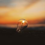 A light bulb reflecting the sunset over a blurred background, symbolizing ideas and innovation.