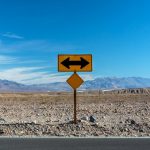 A road sign indicating direction options in a barren landscape